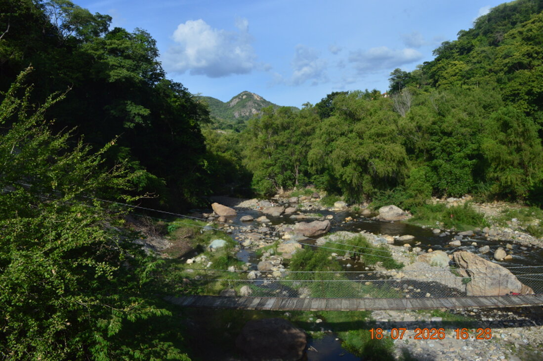 Paisaje de montañas y valle con un puente y un pueblo al fondo